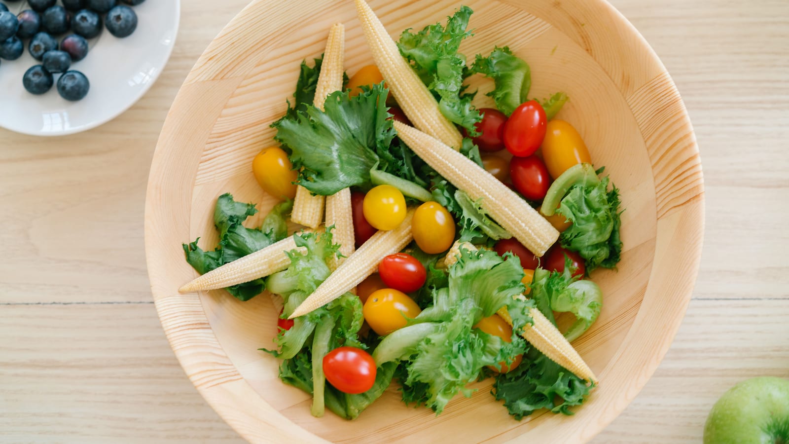 Fresh vegetables and a prepared salad bowl on a wooden table — 5 foods that help maintain a healthy weight at OC Weight Loss