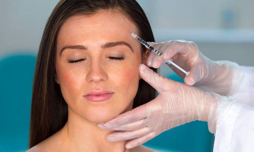 Beautiful young woman receiving botox injection.